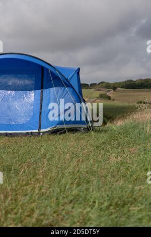 Ein einziges modernes blaues Zelt mit verschiedenen Kulturen und Winkeln In einem Feld mit Kopieplatz, um im Camping zu verwenden Geschichten Stockfoto