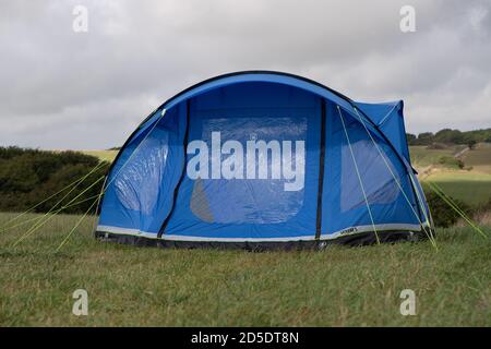 Ein einziges modernes blaues Zelt mit verschiedenen Kulturen und Winkeln In einem Feld mit Kopieplatz, um im Camping zu verwenden Geschichten Stockfoto