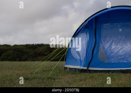 Ein einziges modernes blaues Zelt mit verschiedenen Kulturen und Winkeln In einem Feld mit Kopieplatz, um im Camping zu verwenden Geschichten Stockfoto