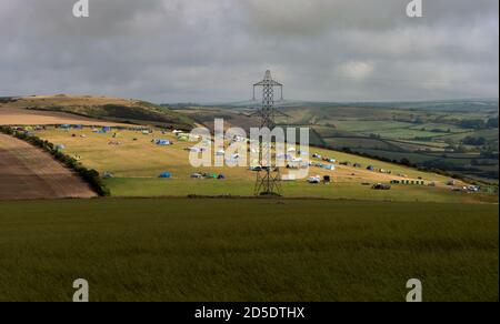 Ein Blick über die Dorset Landschaft mit einem Campingplatz von Zelten in der Ferne und ein Gitter-Strom-Turm . Stockfoto