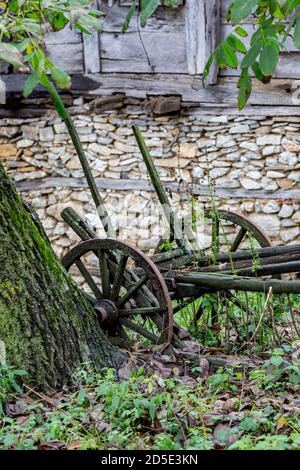 Reisefoto von verlassenen alten Wagen in Form vor Steinhaus bedeckt, ländliche Landschaft, Strandzha Berg, Bulgarien, Holzbohlen Fassade Stockfoto