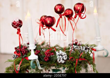 Neue Jahr-Kopie Space Card. Ein weihnachtlicher grüner Kranz aus frischen Nadeln mit roten fliegenden Kugeln, weißen Zapfen, Kerzenleuchtern, Eberesche, steht auf dem Boden. Stockfoto