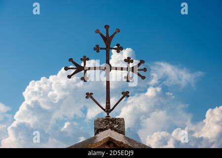 Mittelalterliches christliches Kreuz in Schmiedeeisen auf einem blauen Himmel mit Wolken. Verona, UNESCO-Weltkulturerbe, Venetien, Italien, Europa. Stockfoto