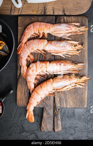 Set von King Shrimps mit Zutaten für Paella auf schwarzem texturierten Hintergrund, Draufsicht Stockfoto