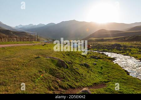 Berglandschaft mit einem Fluss. Heißer Sommertag, grünes Tal umgeben von Bergen. Kirgisistan. Stockfoto