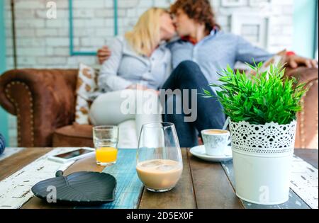 Getränke auf einem Couchtisch mit einem Paar küssen Stockfoto