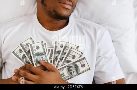 Afrikanischer Mann Schlafen Holding Geld Liegen Im Bett Zu Hause Stockfoto