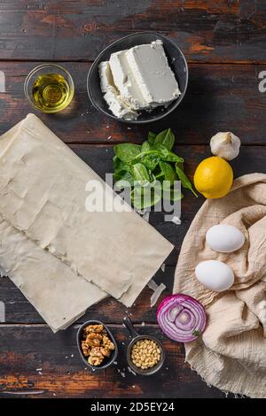 Griechische spanakopita Zutaten Filo Spinat Eier Feta Draufsicht auf Dunkler Holzhintergrund Stockfoto