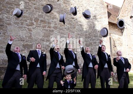 Top-Hüte in die Luft geworfen in der Feier bei einer Hochzeit, mit Bräutigam, Groomsmen und Page Boy in Anzügen mit Schwanz Stockfoto