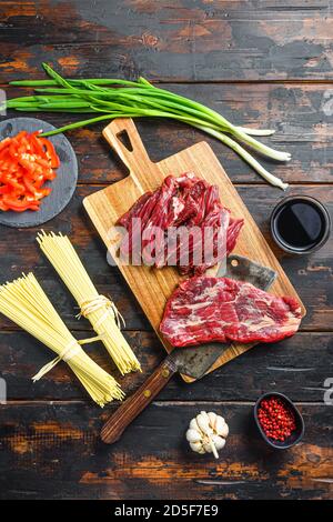 Kochen Zutaten für Stir braten Nudeln mit Gemüse und Rindfleisch. Machete Steak und Nudeln auf Holzhintergrund. Stockfoto