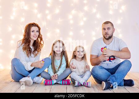 Glückliche Familie haben Spaß, Herumtäuschen auf dem Hintergrund der gelben Girlanden von Lichtern und Bokeh Weihnachtsbaum Äste. Guter Neujahrsgeist. Eltern Stockfoto