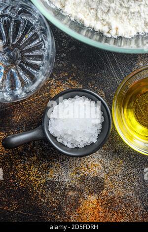 Zutaten für den Teig, Mehl Öl Wasser und Salz auf dunkles Hintergrund. Stockfoto