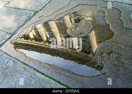 Spiegelung des Royal Crescent in der Stadt Bath, Somerset, Großbritannien, spiegelte sich in einer Pfütze auf dem Steinpflaster draußen wider Stockfoto