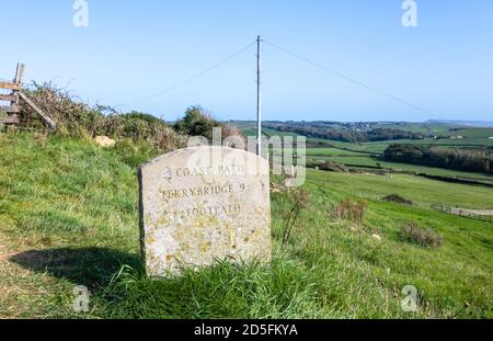 Steinwegmarkierung, die auf Ferrybridge zeigt, das auf einem Feld auf dem South-West Coast Path an der Heritage Coast, Abbotsbury, Dorset, liegt Stockfoto