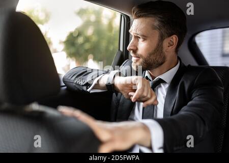 Hübscher bärtiger Mann im Anzug, der im Auto sitzt Stockfoto