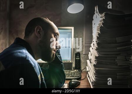 Ein junger Mann in einem Overall sieht müde aussehen Die anstehenden Arbeiten Stockfoto