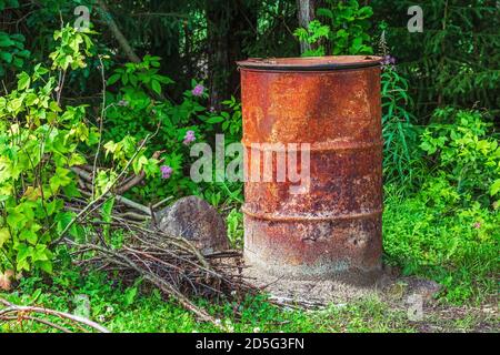 Alte rostige Eisenfass verwendet, um Müll in einem Vorstadtgarten Grundstück zu verbrennen. Stockfoto