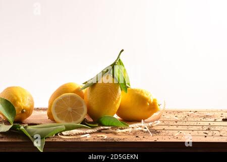 Gruppe von frisch gepflückten Erntezitronen auf Holztisch aus einem Korb isoliert weiß. Vorderansicht. Horizontale Zusammensetzung. Stockfoto