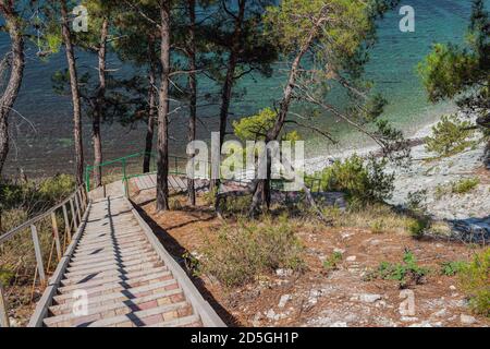 Eine Treppe zum Meer auf den Felsen führt zu einem wilden Strand. Straße durch den Wald und Camping. Der Stadtrand von Gelendzhik. Russland Stockfoto