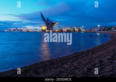 Hafen von Felixstowe, Suffolk, Kräne laden Container auf Frachtschiffe in der Dämmerung Stockfoto