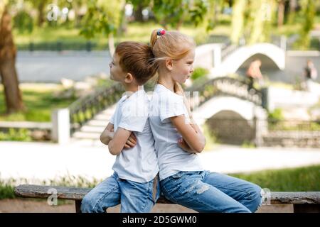 Die Kinder vergehen sich gegenseitig im Park auf der Bank. Stockfoto