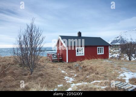 Traditionelle rote Holzhäuser am Ufer des reine Fjords. Wunderschöne Winterszene auf der Insel Vestvavoy. Malerischer Blick auf die Lofoten-Inseln am Morgen, Stockfoto