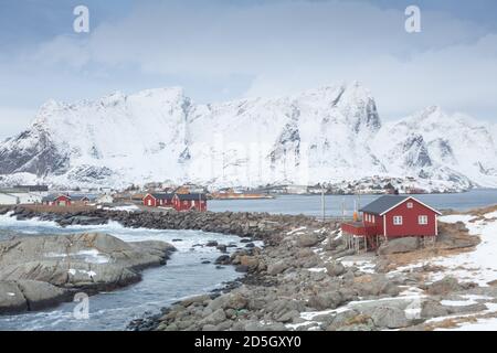 Traditionelle rote Holzhäuser am Ufer des reine Fjords. Wunderschöne Winterszene auf der Insel Vestvavoy. Malerischer Blick auf die Lofoten-Inseln am Morgen, Stockfoto