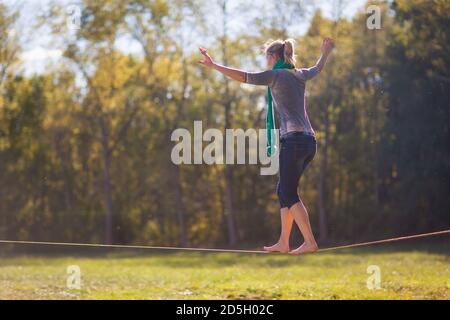 Mann Wandern, Springen und Balancieren am Seil im Park Sport eine Drahtseilbahn oder Slackline im Freien in einem Stadtpark im Sommer Slacklining, Balance, Training Stockfoto