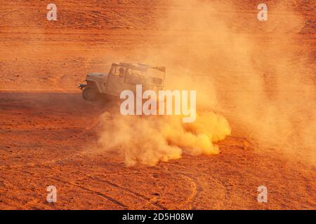 Wadi Rum, Jordanien 03/31/2010: Ein Offroad-Fahrzeug für Wüstensafari beschleunigt sich in der Wüste mit aggressiven Kurven, die große rote Wolken erzeugen Stockfoto