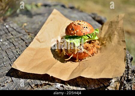 Käseburger mit zerfetztem Fleisch und frischem Salat. Auf einem Stumpf im Wald. Stockfoto