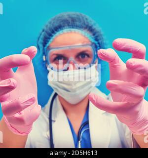 Hände eines Arztes mit einem wütenden Blick werden zum Patienten wie in einem Horrorfilm, blauer Hintergrund gezogen. Konzept zu Hause bleiben. Eine Krankenschwester greift in med nach Ihnen Stockfoto