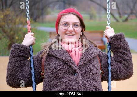 Junge Frau in Herbstkleidung auf Schaukel Stockfoto