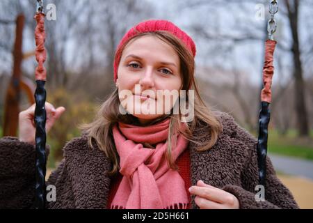 Junge Frau im Herbstpark auf einer Schaukel sitzend, Gesicht Nahaufnahme Stockfoto