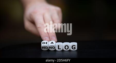 Hand dreht Würfel und ändert das deutsche Wort 'Monolog' (Monolog) in 'Dialog'. Stockfoto
