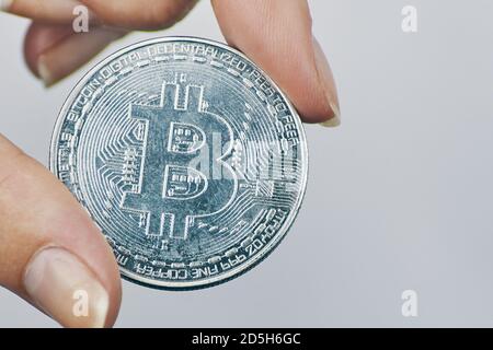 Frau hält Bitcoin Münze. Silbermünze mit Bit-Münze Symbol. Anstieg der Kryptowährung. Neues Konzept für virtuelles Geld. Mining- oder Blockchain-Technologie. Stockfoto