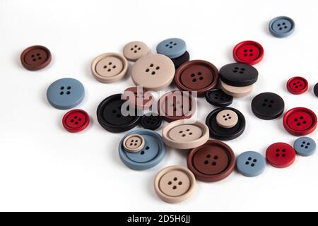 Farbstapel braun, beige, grau, rot, schwarz Kunststoff matt Knöpfe auf weiß, schöne Nadelarbeit, Minimalismus. Zum Nähen verwenden. Leerzeichen für Text. Stockfoto