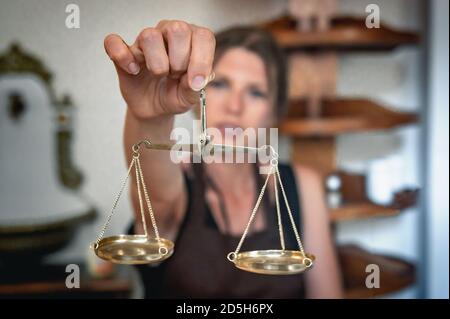 Waagen der Gerechtigkeit in den Händen einer jungen Frau. Der Apotheker wiegt die Medikamente. Stockfoto