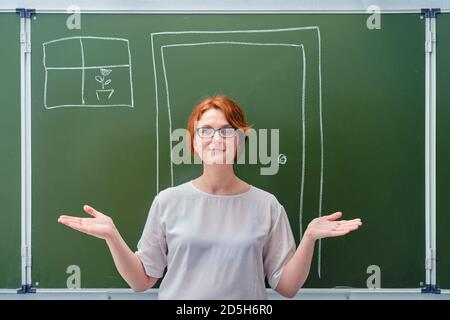 Glücklicher Lehrer auf dem Hintergrund einer Tür, die mit Kreide auf einer Tafel gezeichnet ist. Willkommen zurück zur Schule Konzept Stockfoto