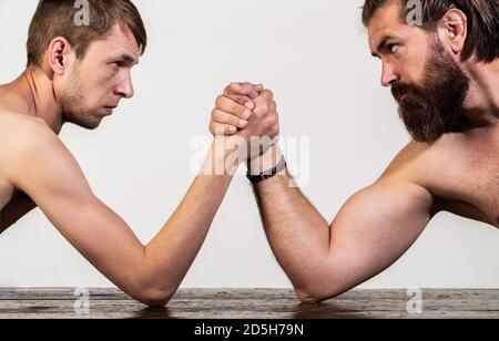 Zwei Männerhände umklammten Arm Wrestling, stark und schwach, ungleiche Übereinstimmung. Stark muskulös bärtigen Mann Arm Ringen ein mickrigen schwachen Mann. Arme ringen dünn Stockfoto