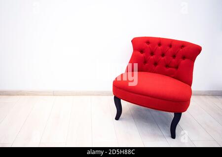 Einzelner Sessel aus rotem Samt in minimalistischem Interieur Stockfoto