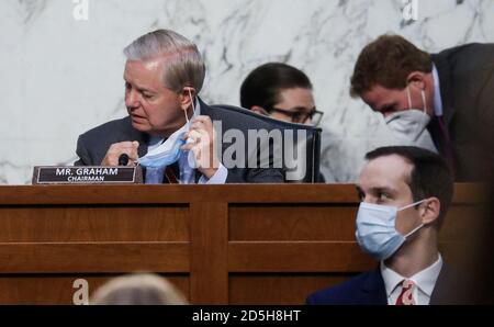 US-Senator Lindsey Graham (Republikaner von South Carolina), Vorsitzender des Justizausschusses des US-Senats, sieht seine Gesichtsmaske während des zweiten Tages der Anhörung des Ausschusses zur Bestätigung der Ernennung von Richterin Amy Coney Barrett zum US-Obersten Gerichtshof auf dem Capitol Hill in Washington, USA, 13. Oktober, 2020. Quelle: Leah Millis/Pool via CNP /MediaPunch Stockfoto