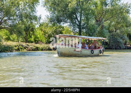 VILKOVE, UKRAINE - 05. AUGUST 2020: Menschen reisen mit alten hölzernen Motorboot entlang Ankudinovo Kanal. In der Nähe von Biosphärenreservat, Schwarzes Meer und Donau Del Stockfoto