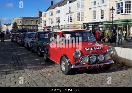 Ein Blick auf einen Doppelmotor 1965 Austin Mini Copper S mit anderen Minis, die am Wells Market Square geparkt sind Stockfoto