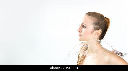 Hübsche Frau mit Wasserspritzer. Schöne Model Frau mit einem Spritzer Wasser. Schöne lächelnde Mädchen unter Wasser mit frischer Haut auf blauem Hintergrund. Sk Stockfoto