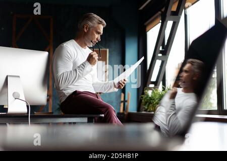 Casual grauhaarige Reife Mann lesen Papier in seinem Büro. Stockfoto