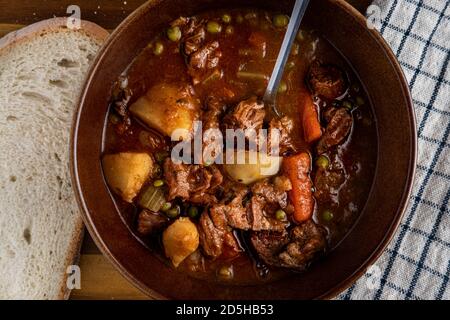 Schüssel mit frisch zubereitetem Rindereintopf mit Rindfleisch, Karotten, Kartoffeln, Sellerie, Zwiebeln, Erbsen und Knoblauch Stockfoto