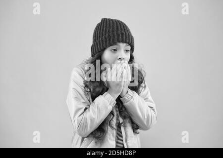 Keine Grippe in diesem Winter. In der kalten Jahreszeit warme Kleidung tragen. Winterferienaktivität. Kleine pinkfarbene Wand. Modischer Stil für Kinder. Strickmütze und Puffer-Mantel. Kleines Mädchen fangen Husten. Es ist so kalt. Stockfoto