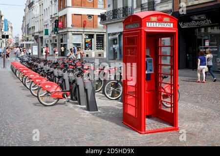 LILLE, FRANKREICH - 18. Juli 2013. Rote britische Telefonbox und kostenloser Fahrradverleih in einer Straße in Lille, Frankreich Stockfoto