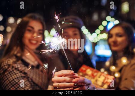 Neujahr und Weihnachten. Frauen Freunde brennende Wunderkerzen in Lviv auf der Straße fair Spaß mit Geschenken. Nahaufnahme Stockfoto