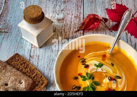 Kürbissuppe mit gerösteten Samen und der sauren Sahne auf Der Holztisch Stockfoto